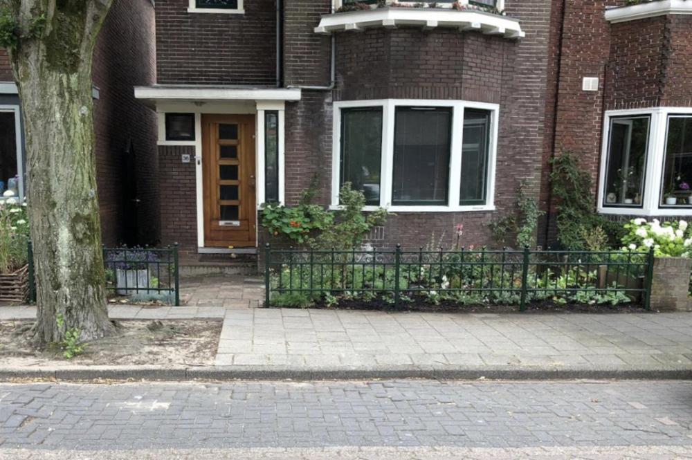 Groen sierhekwerk met krullen langs een tuin