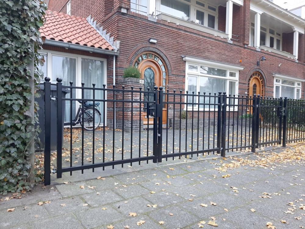 Sierhekwerk met rechte spijlen langs een oprit