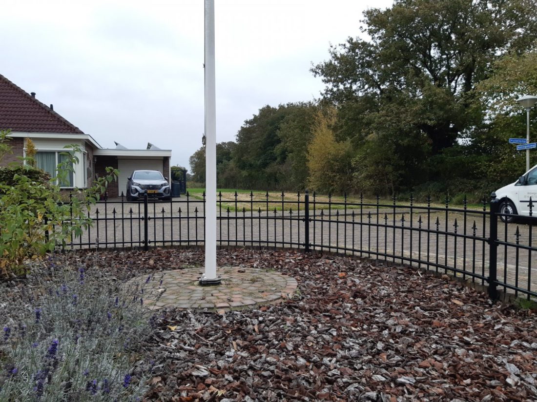 Sierhekwerk met sierlijke spijlen rond een ronde voortuin