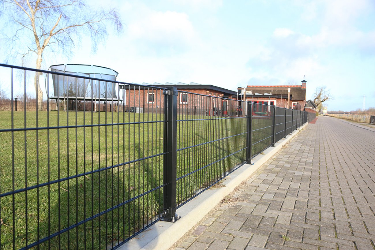 Lang dubbelstaafmat hekwerk langs een pad