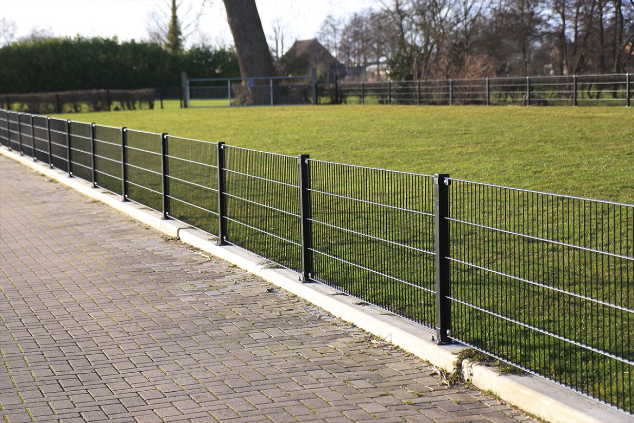 Dubbelstaafmat hekwerk op een opsluitband langs een grasveld