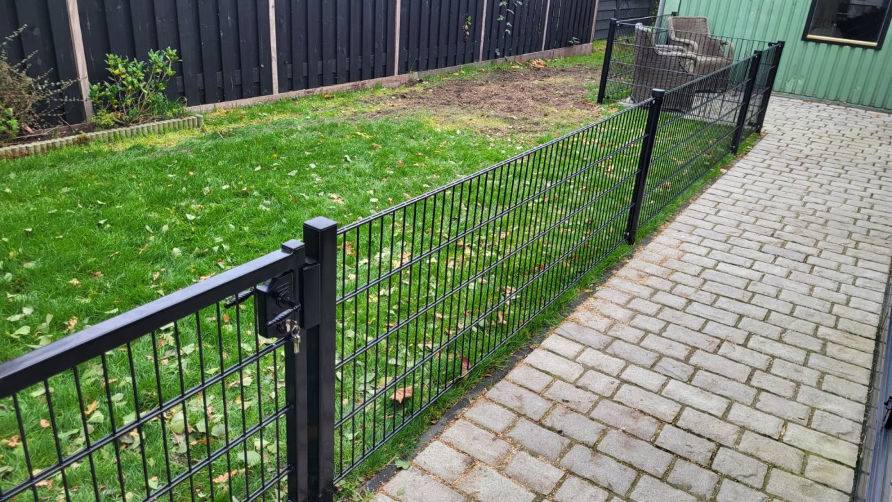 Groen dubbelstaafmat hekwerk langs een tuinpad