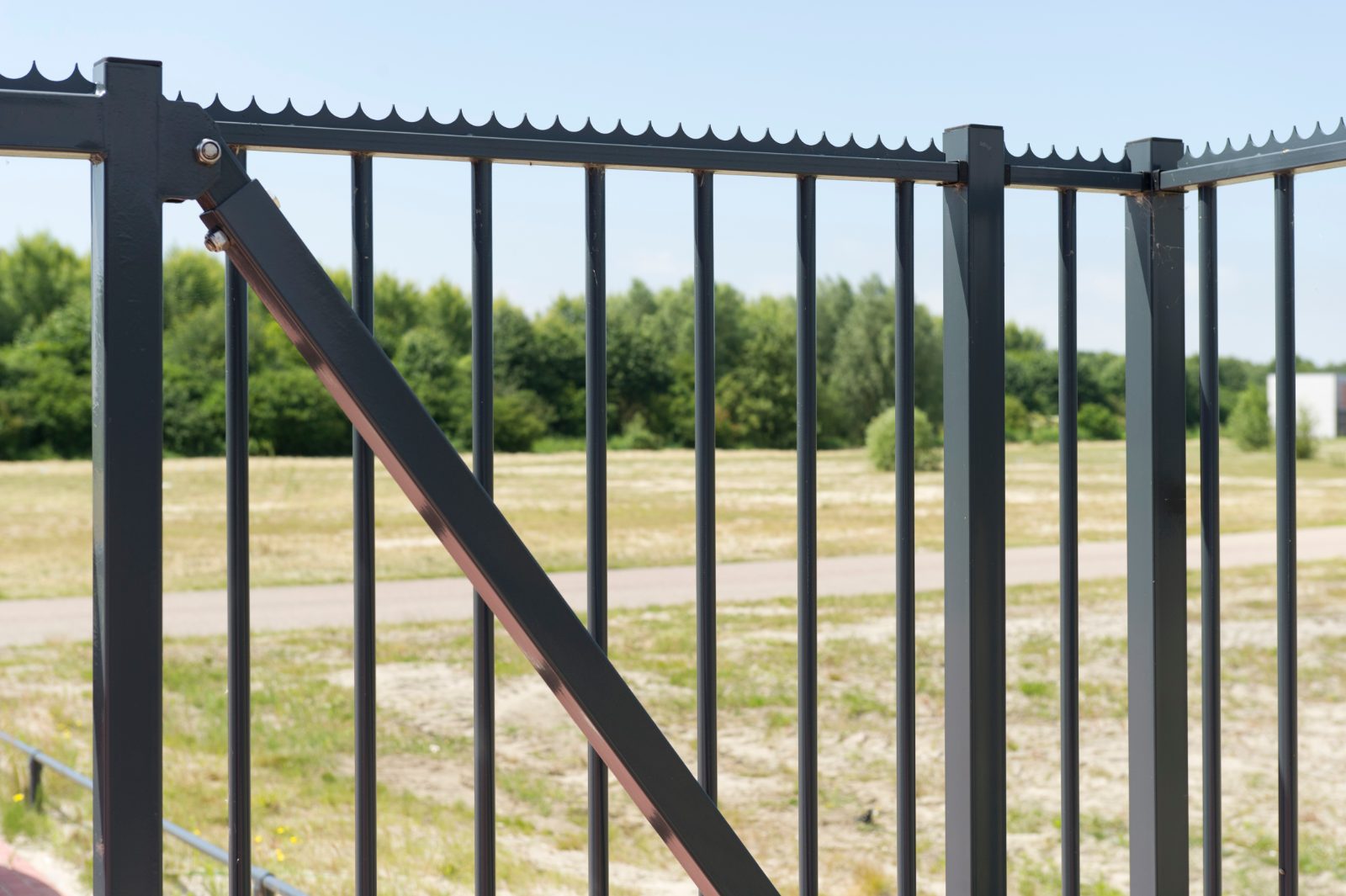 Spijlenhekwerk met poort aan de rand van een veld